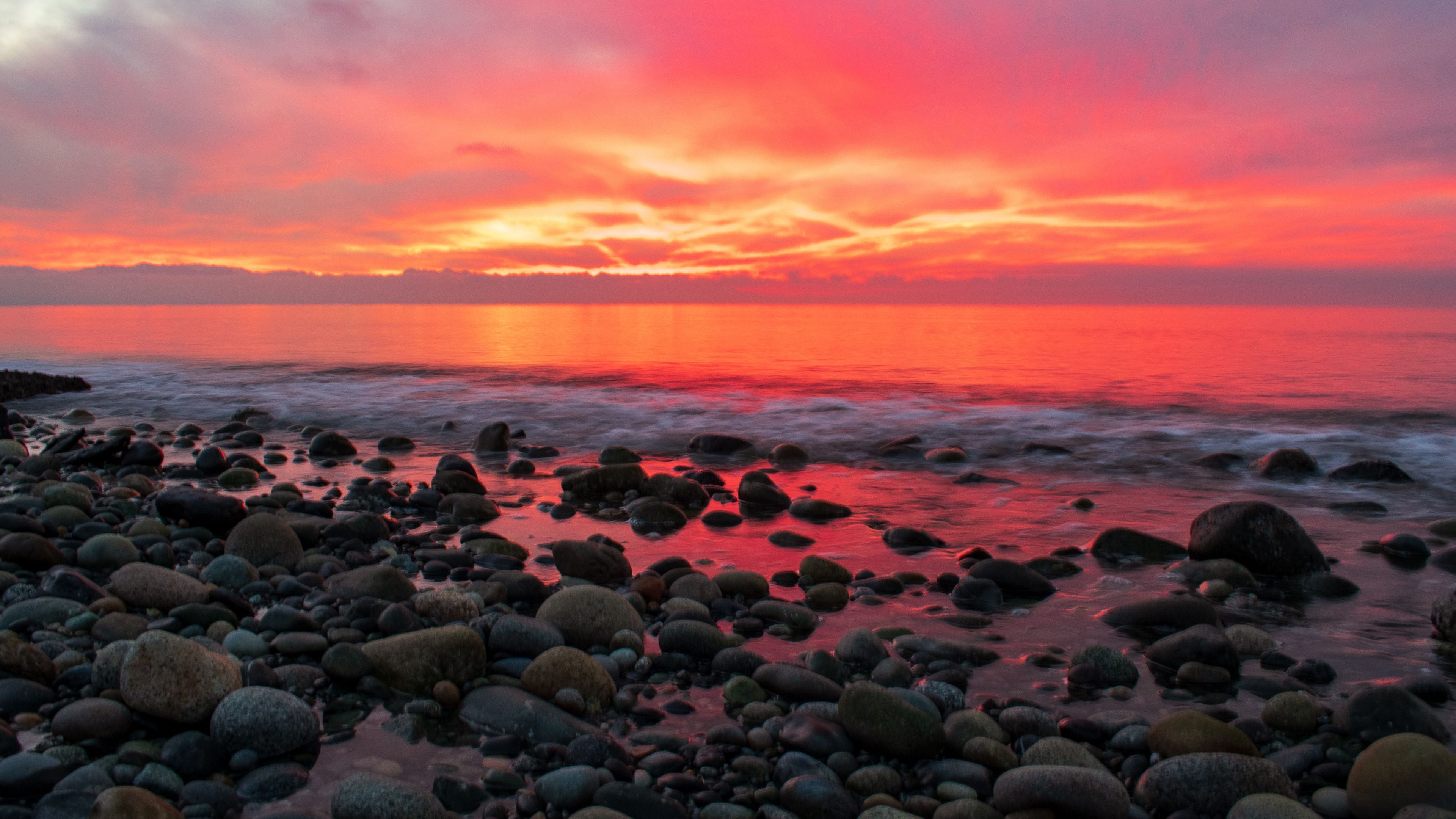 A sunset over a rocky shoreline with a vibrant sky.