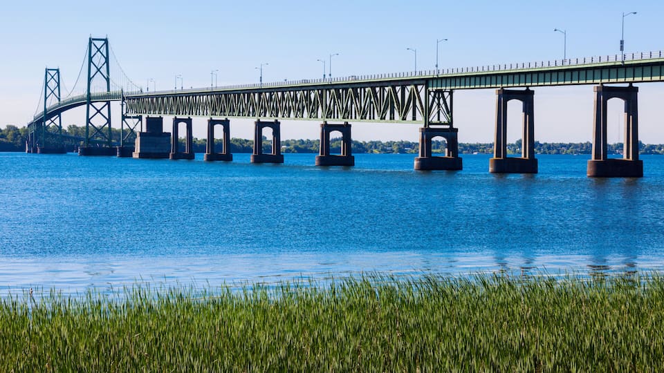 A large steel bridge spanning a river with clear blue water.