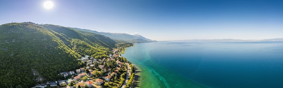 A coastal town nestled between lush green hills and a calm blue sea.