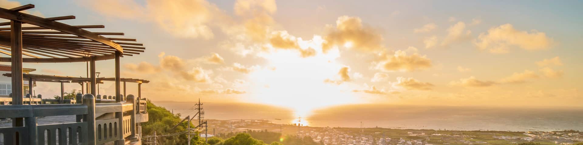 A coastal road with a sunset, a bridge, and a view of a town.