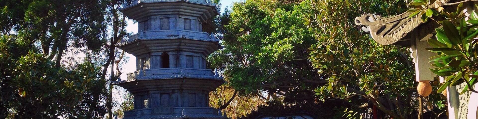 A multi-tiered pagoda surrounded by lush greenery and a stone bridge.