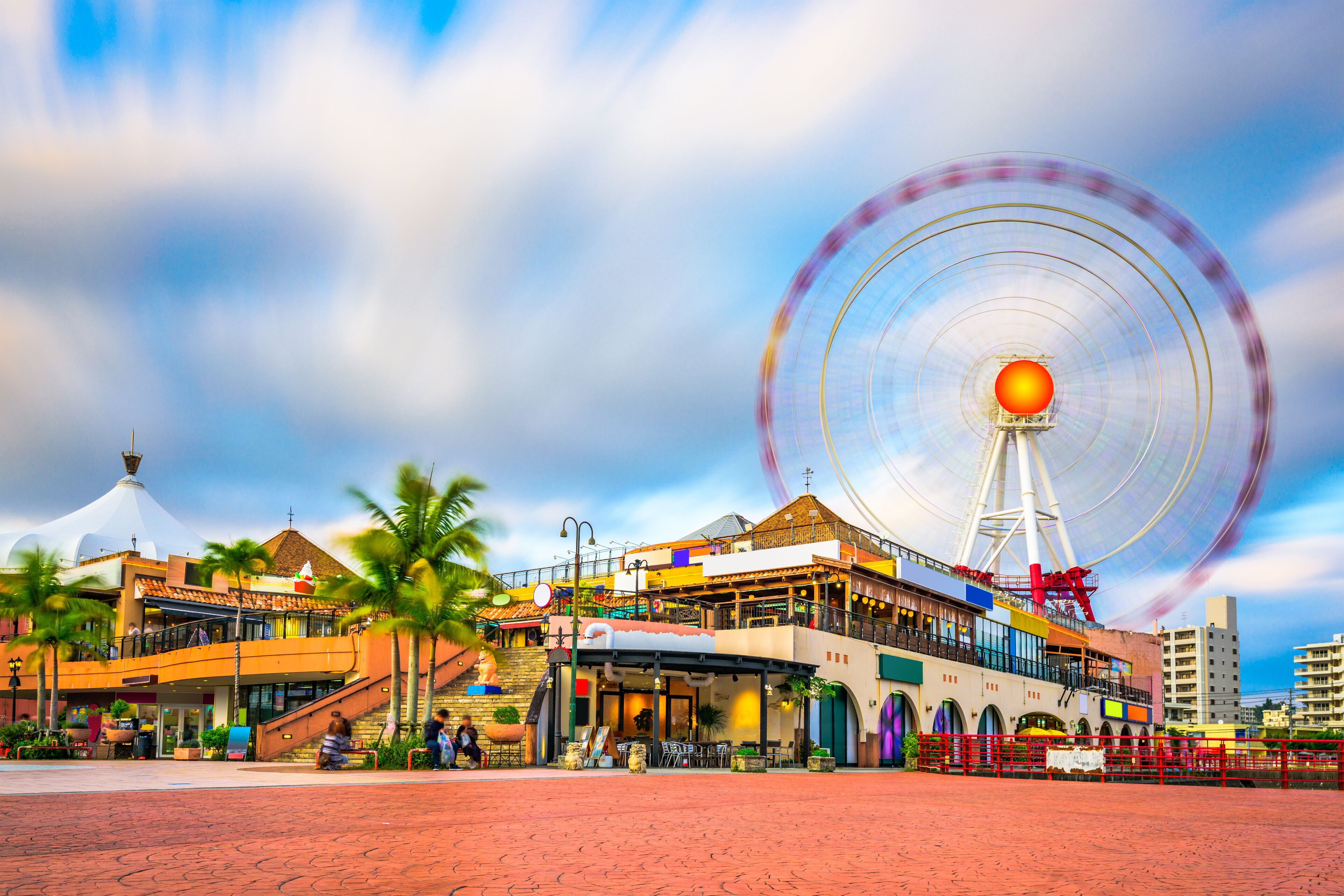 A Ferris wheel, a large white dome, and a building with a sloped roof.
