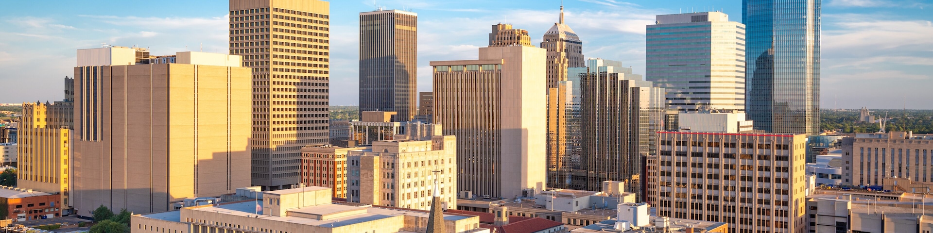 A cityscape with a variety of buildings, including a tall skyscraper and several mid-rise structures.