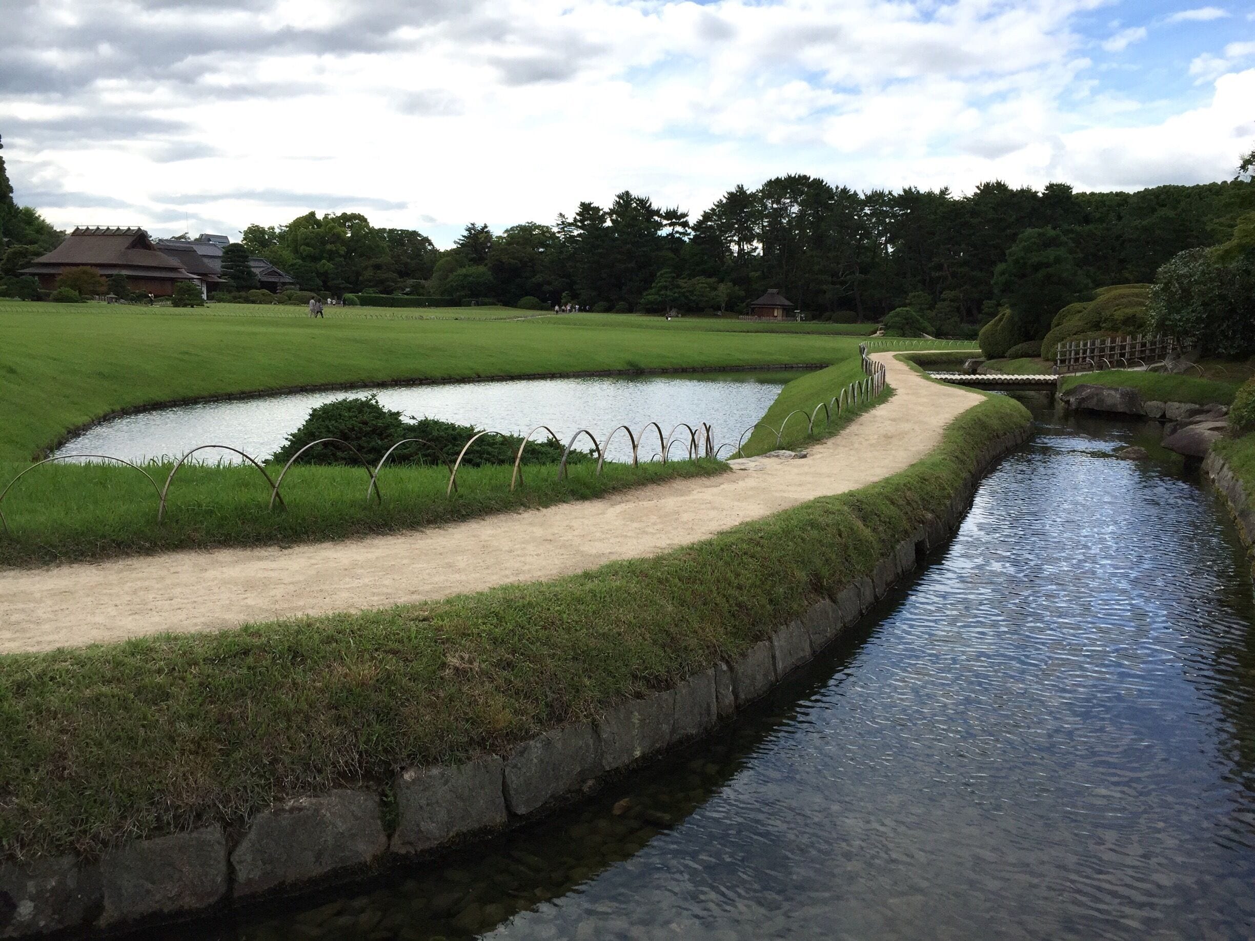 Wikipedia: 
The garden is located on the north bank of the Aashi River on an island between the river and a developed part of the city. The garden was designed in the Kaiyu ("scenic promenade") style which presents the visitor with a new view at every turn of the path which connects the lawns, ponds, hills, tea houses, and streams.

The garden covers a total area of approximately 133,000 square meters, with the grassed area covering approximately 18,500 square meters. The length of the stream which runs through the garden is 640 meters. It features a central pond called Sawa-no-ike (Marsh Pond), which contains three islands purported to replicate the scenery around Lake Biwa near Kyoto.