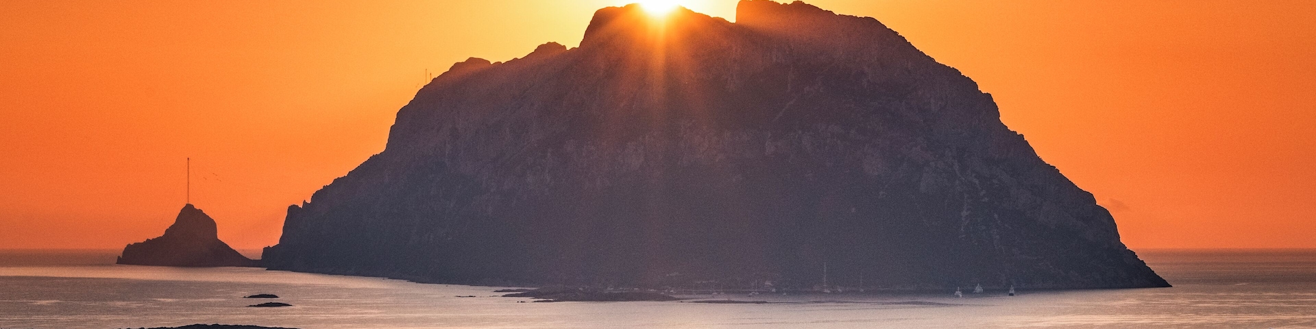Tavolara Island sunrise as seen from Porto San Paolo, Sardinia. This majestic 1800-foot limestone cliff can be seen from many Sardinian beaches. It is a stunning background when enjoying a day at the beach. #Gold