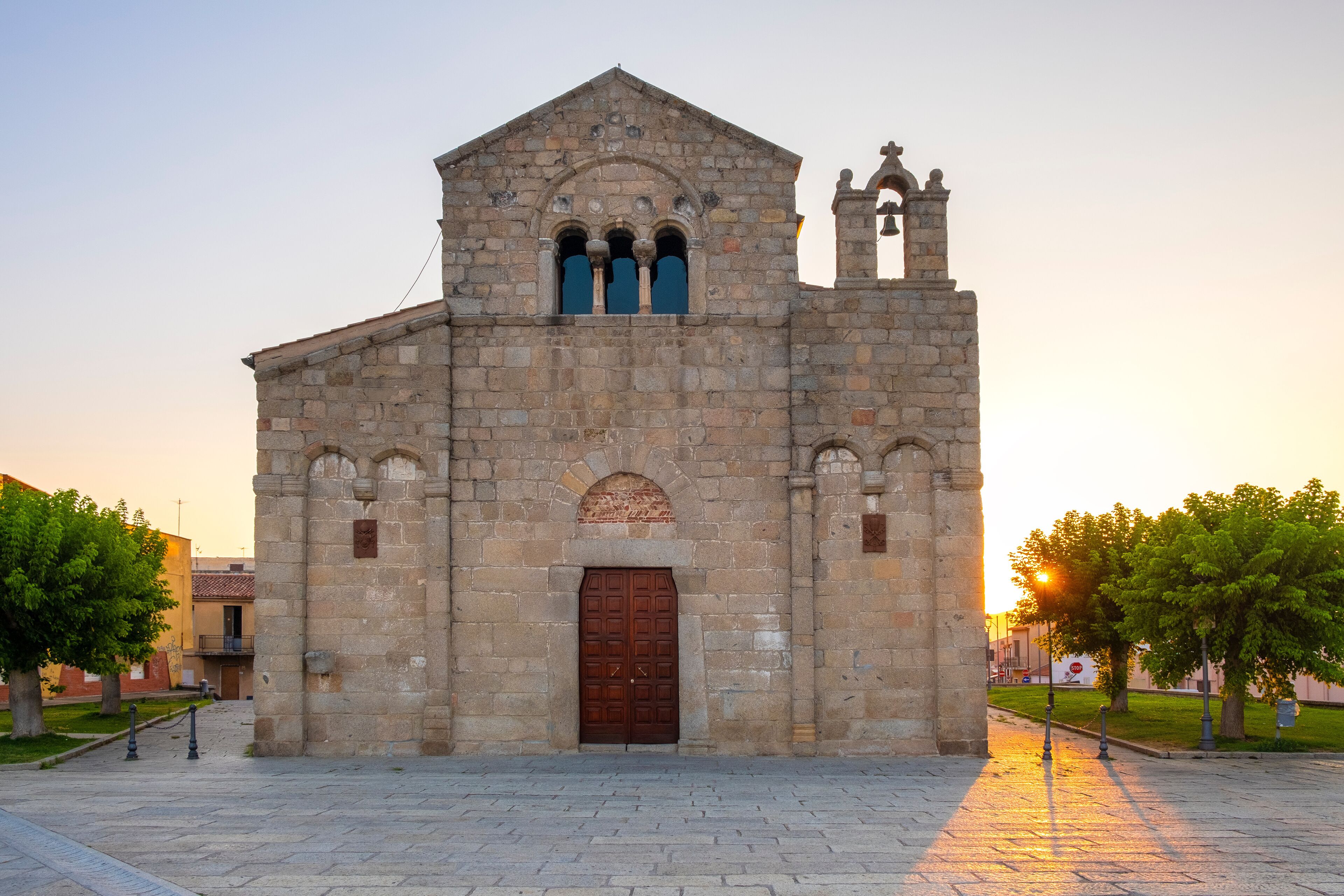A stone church with a bell tower and a large wooden door.