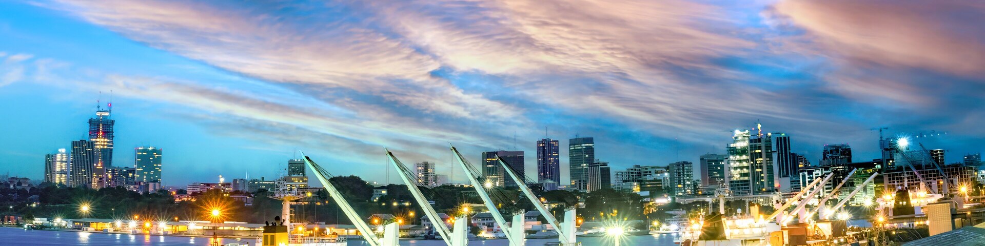 Un puerto al atardecer con un horizonte urbano de fondo.