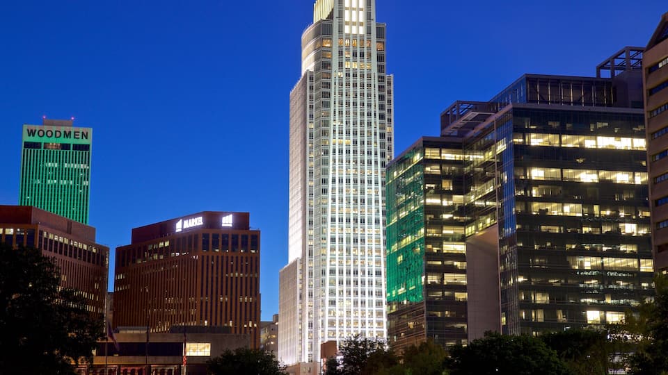 A city skyline with prominent buildings including a tall skyscraper with a unique design, a building with 'MARKEL' signage, and another with 'WOODMEN' signage.