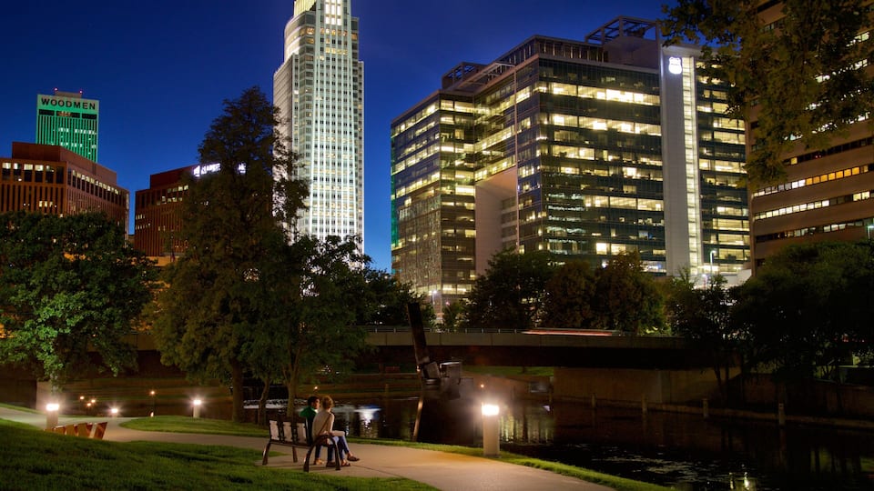 A cityscape at night with illuminated buildings, a river, and a bridge.