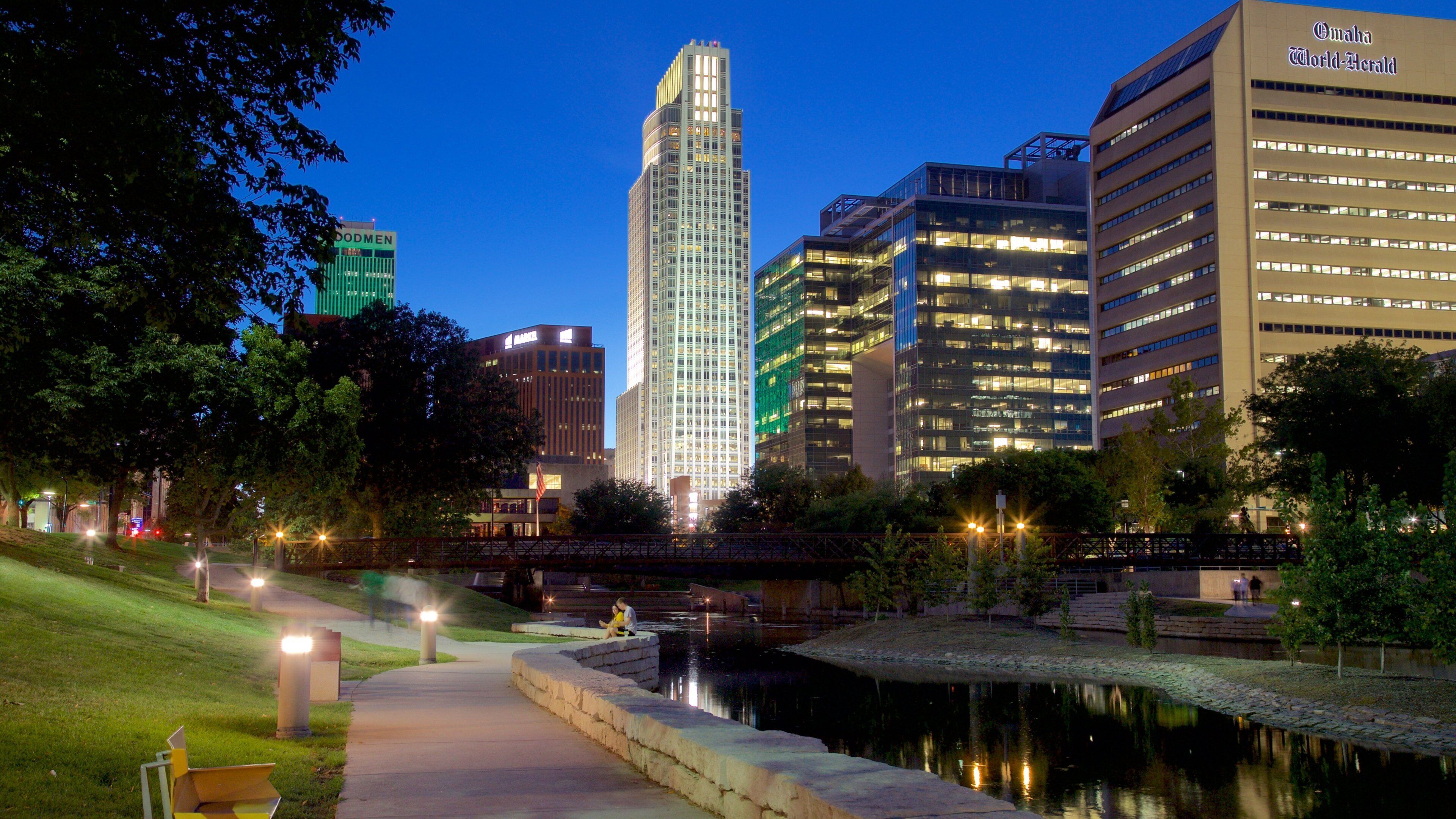 A cityscape at dusk with prominent buildings, a river, and a park area.