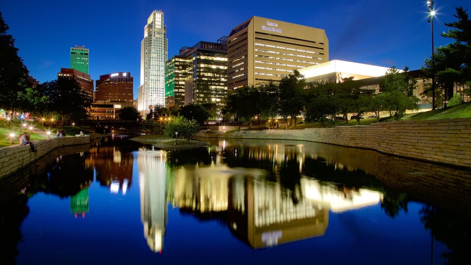 A cityscape at night with a calm river reflecting buildings.