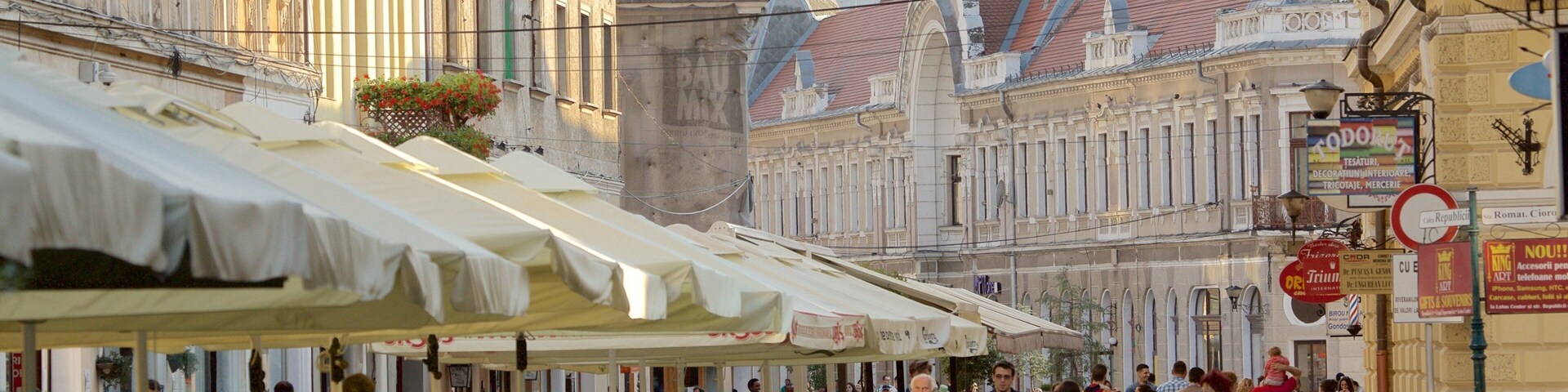 Uma rua movimentada com cafés ao ar livre, edifícios históricos e pedestres.