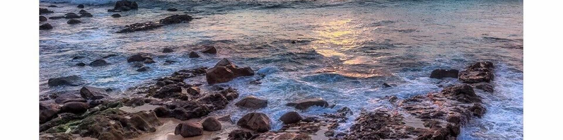 A rocky shoreline with waves at sunset.