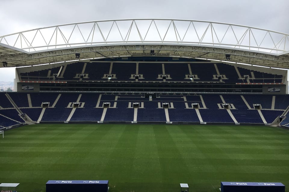 Uno stadio di calcio vuoto, con un campo verde e posti a sedere blu.