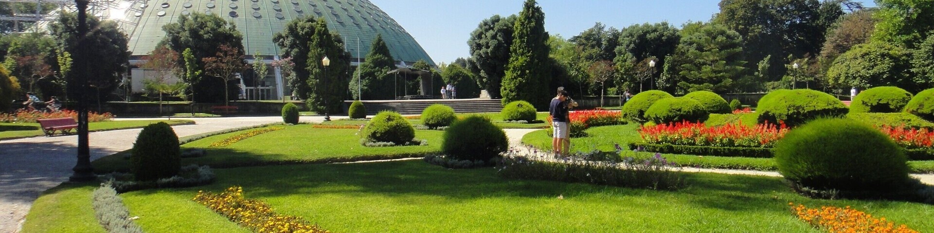 A large green dome structure surrounded by manicured gardens with neatly trimmed hedges and flower beds.