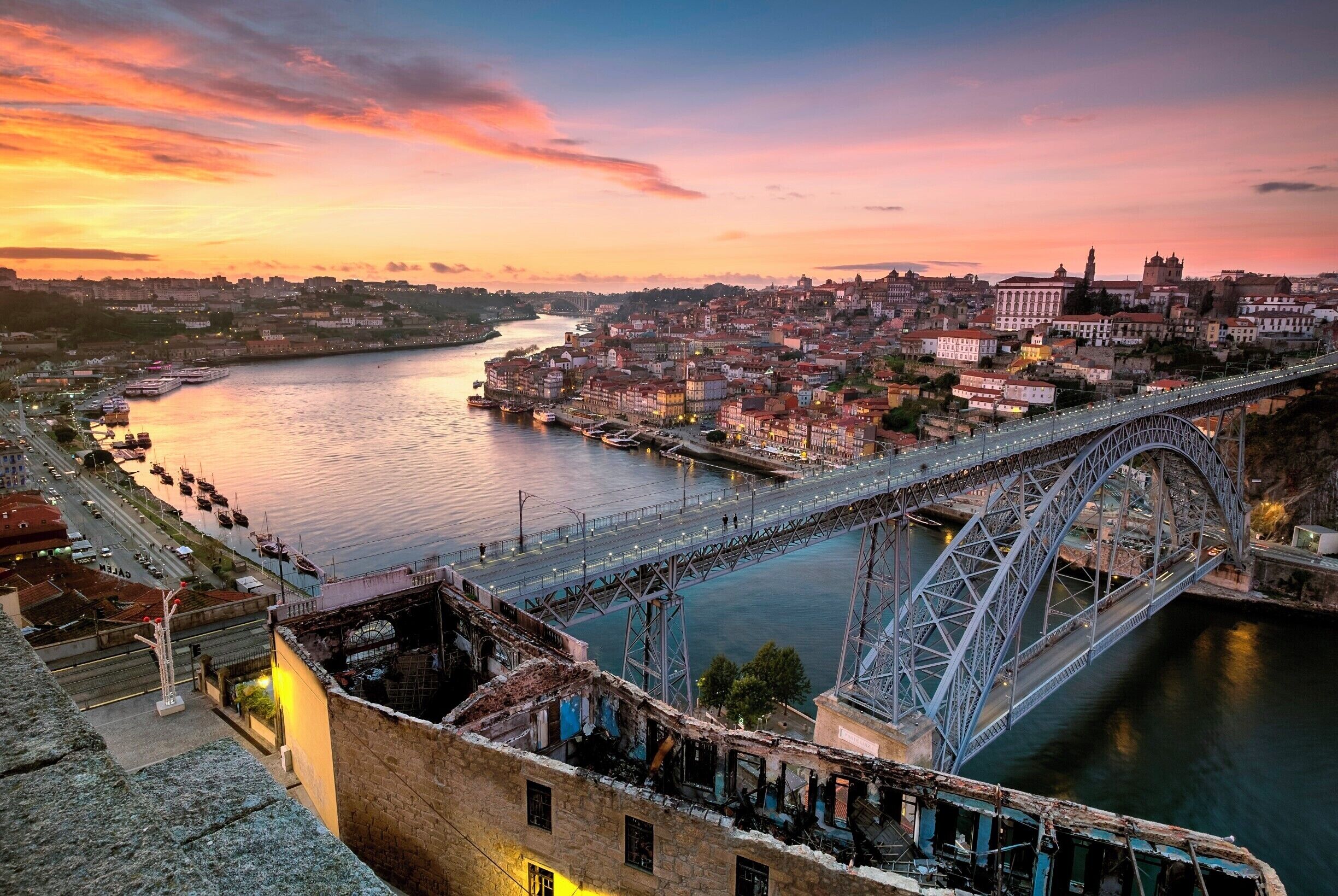 A sunset over a city with a prominent bridge spanning a river.