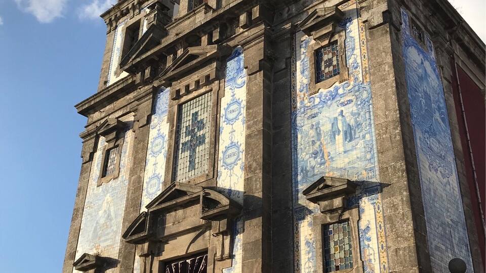 A historic building with blue and white tiled facade, ornate architectural details, and a clock tower.
