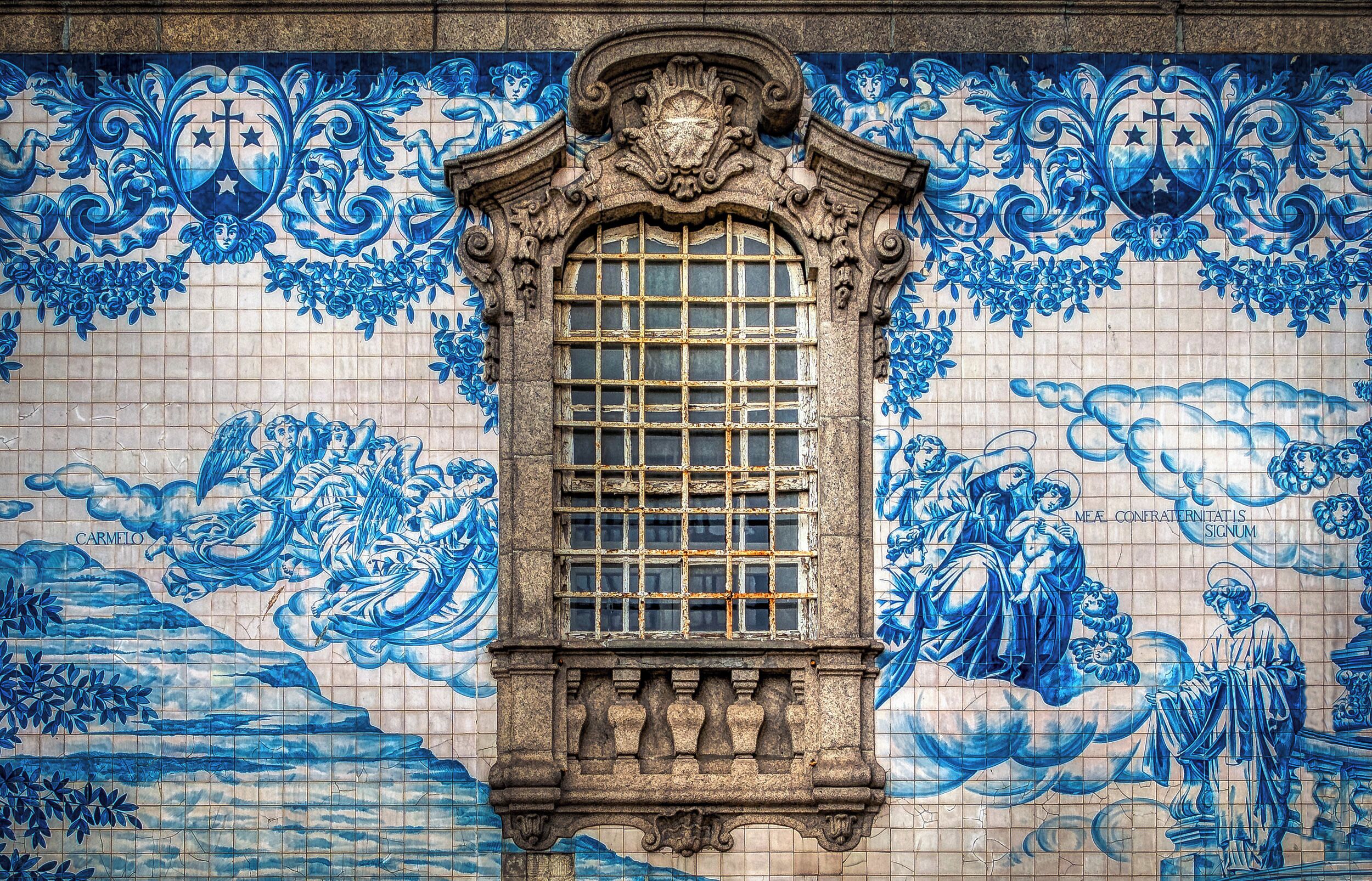 "Azulejo" is a form of Spanish and Portuguese painted tin-glazed ceramic tilework. Azulejos are found on churches, palaces, ordinary houses, schools, and nowadays, restaurants, bars and even railways or subway stations. They were not only used as an ornamental art form but also had a specific functional capacity like temperature control in homes. I photographed this beautiful artwork outside of the "Igreja do Carmo" church in Porto, Portugal.