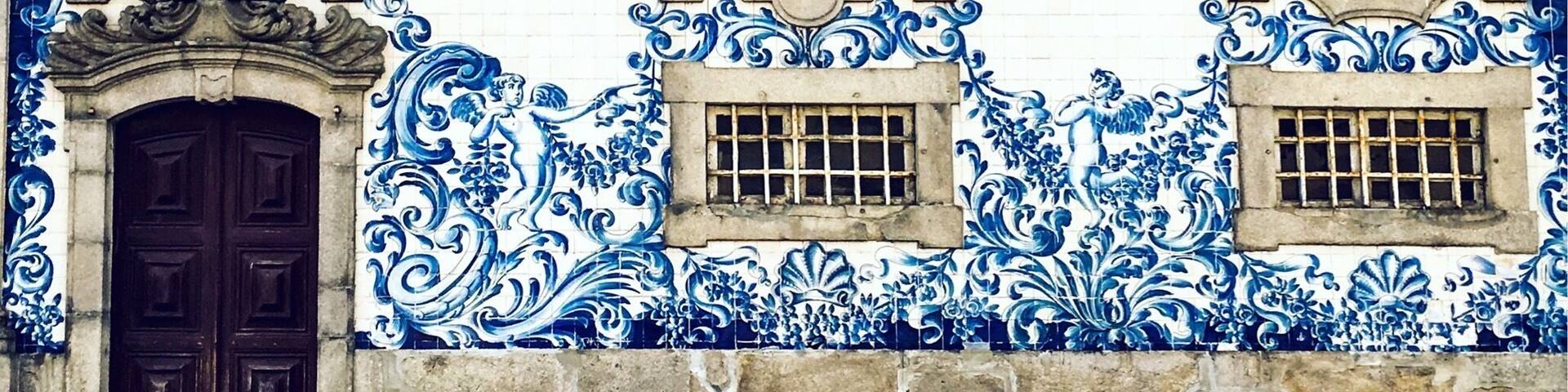 A building with blue and white tiles, ornate window frames, and a dark wooden door.