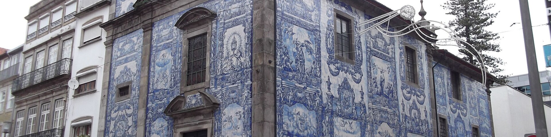 Un edificio con detalles en azulejos azules y blancos, una torre de campanas y una señal de calle.