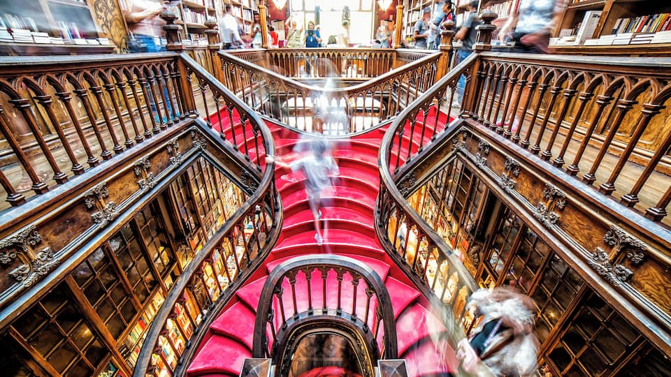 Una imponente escalera en una biblioteca rodeada de estanterías.