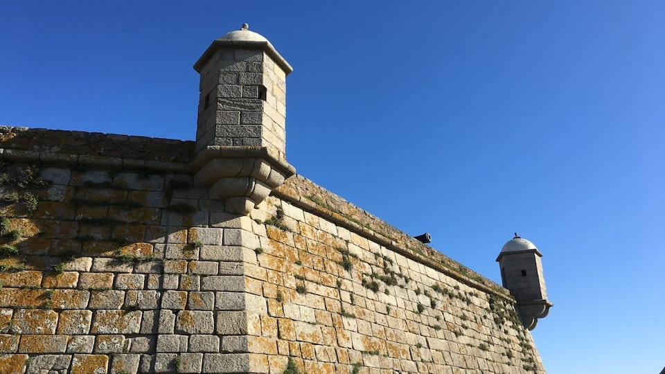 A stone wall with a watchtower and a smaller tower.