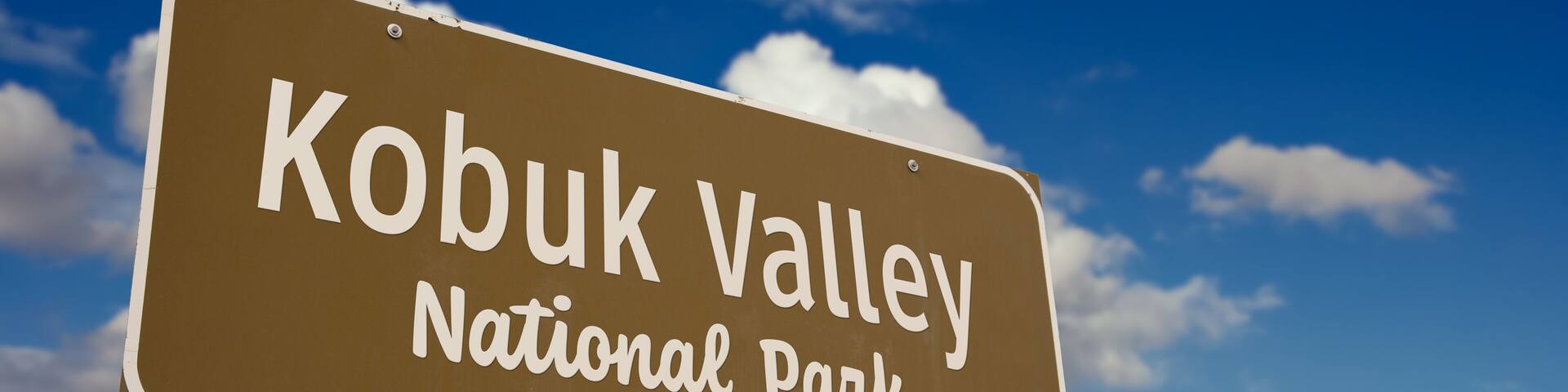 Kobuk Valley National Park (Alaska) Road Sign Against Blue Sky and Clouds.
