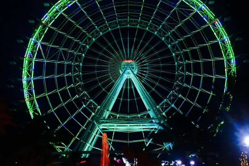 A large Ferris wheel with green lights at night.