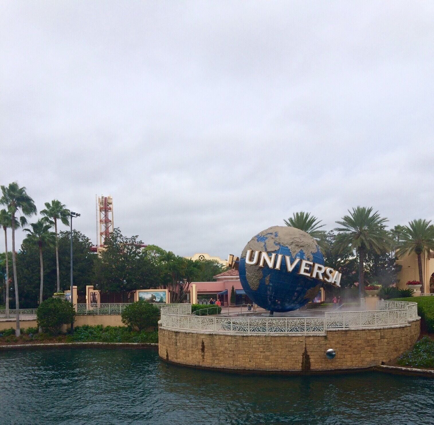 A large globe with "UNIVERSITY" written on it, surrounded by palm trees and a water feature.