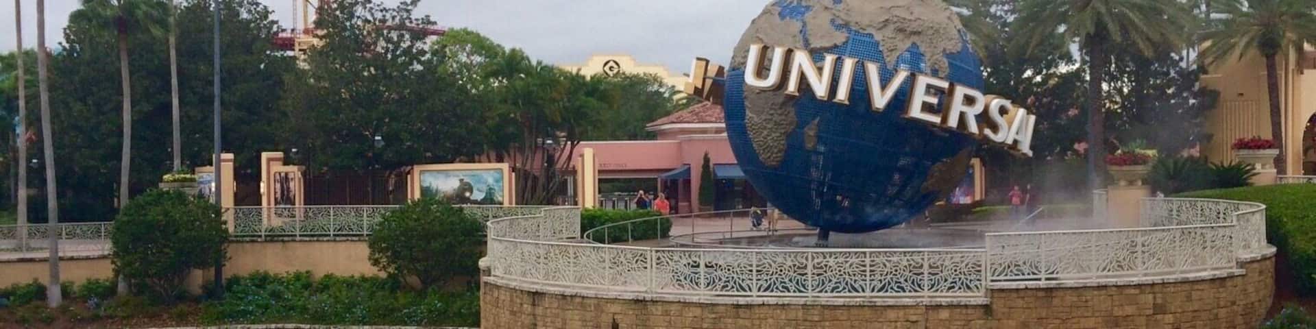 A large globe with "UNIVERSITY" written on it, surrounded by palm trees and a water feature.