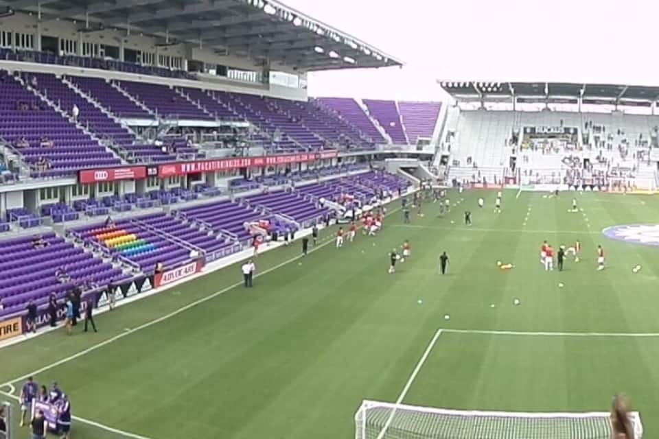 A football stadium with purple seating and a green field.