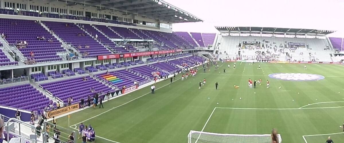A football stadium with purple seating and a green field.