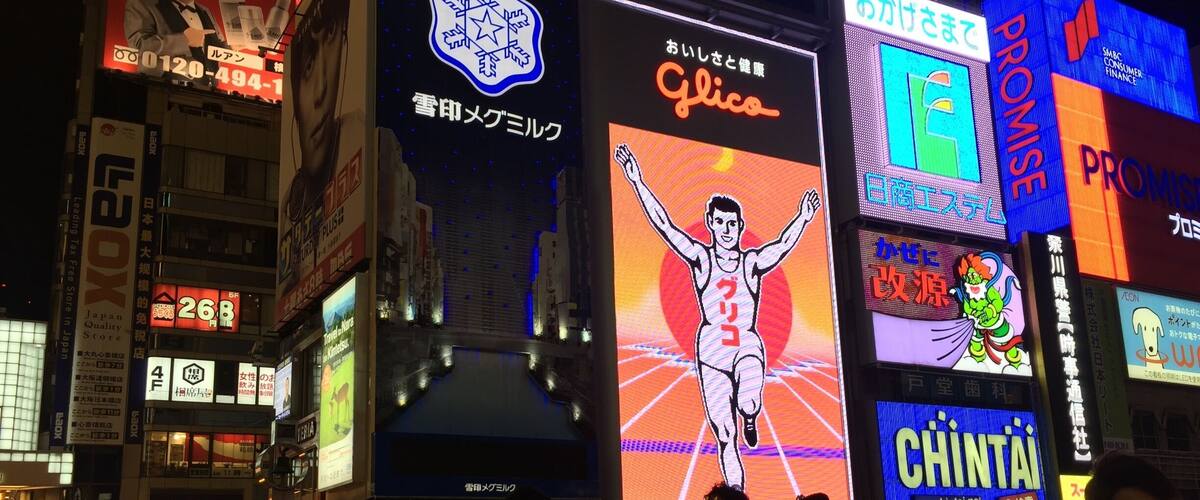 The Glico board lights up orange and blue at night.
