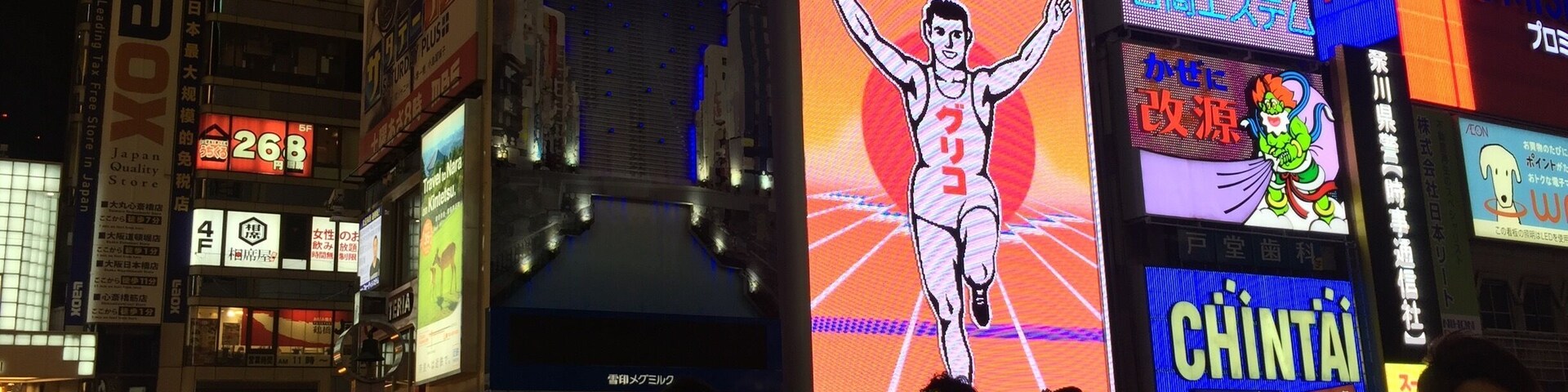 The Glico board lights up orange and blue at night.