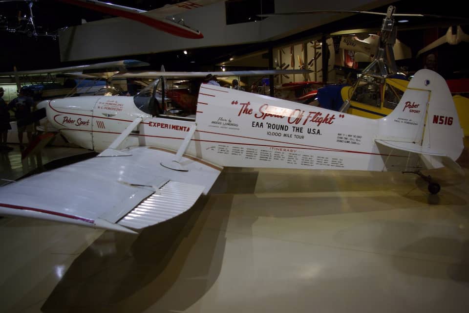 Un aeroplano Piper Sport d'epoca con un cartello che riporta la scritta "The Spirit of Flight" e "EAA 'Round the U.S.A.", tour di 16.000 chilometri.