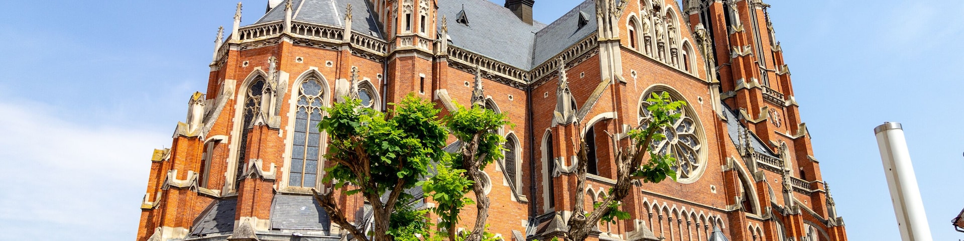 Uma igreja de tijolos grande e ornamentada, com múltiplas torres e um imponente campanário.