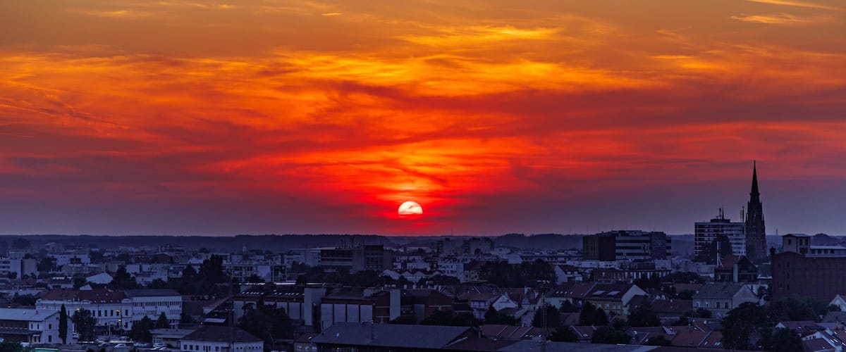 A sunset over a cityscape with a prominent church spire.