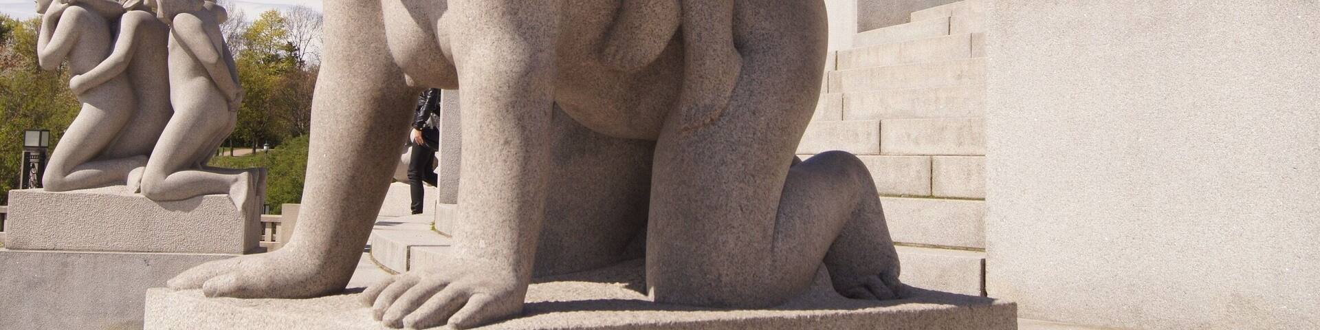 A stone sculpture of a woman holding a child, with other figures in the background.