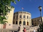 A historic building with a round facade, arched windows, and a flag.