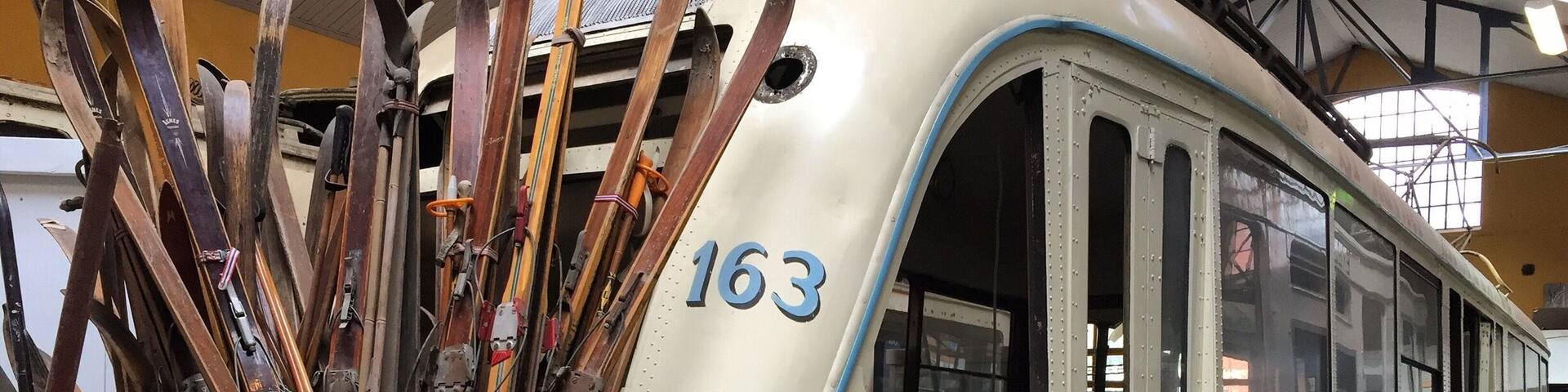 A vintage tram with skis stored in a compartment, marked with the number 163.