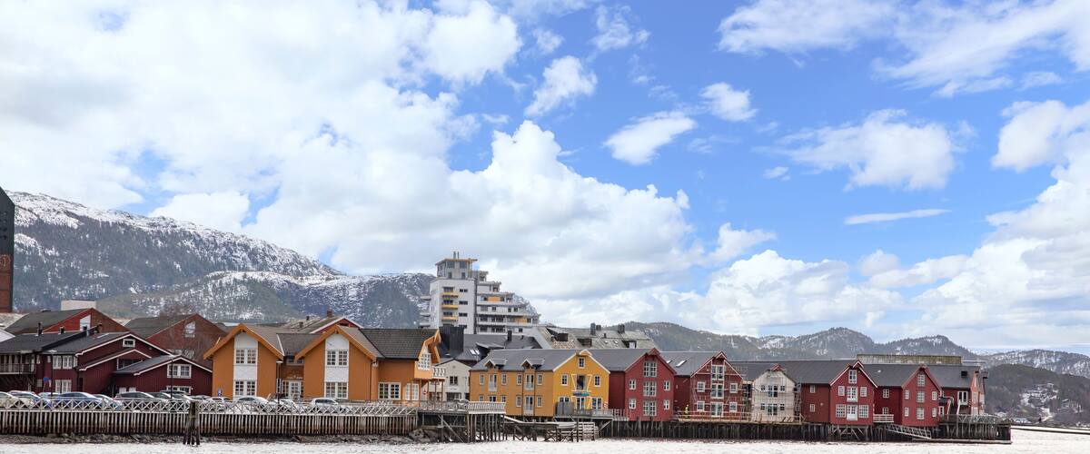 A coastal town with colorful buildings and snow-capped mountains in the background.