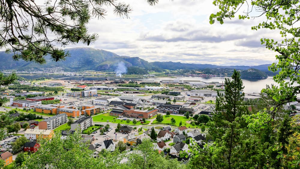 Une ville traversée par une rivière, entourée de montagnes, et où se côtoient des bâtiments résidentiels et commerciaux.