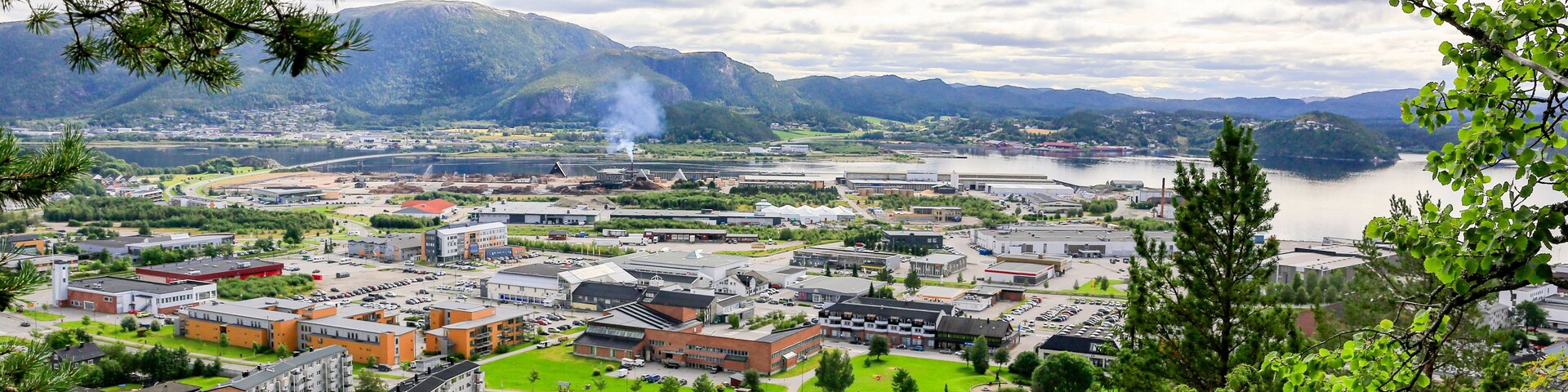 Un pueblo con río, montañas y una combinación de edificios residenciales y comerciales.