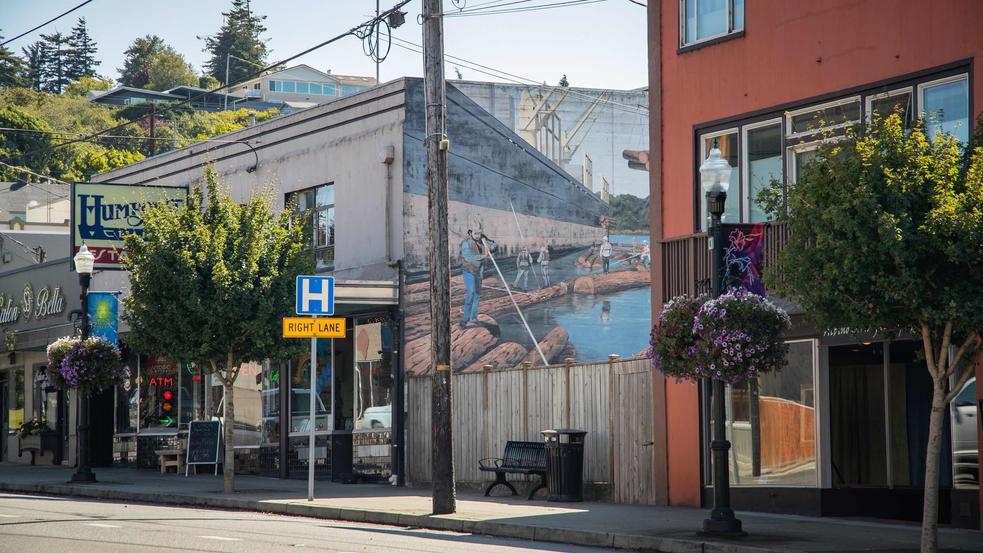 A street with a hospital sign, a right lane sign, and a mural of a river scene.