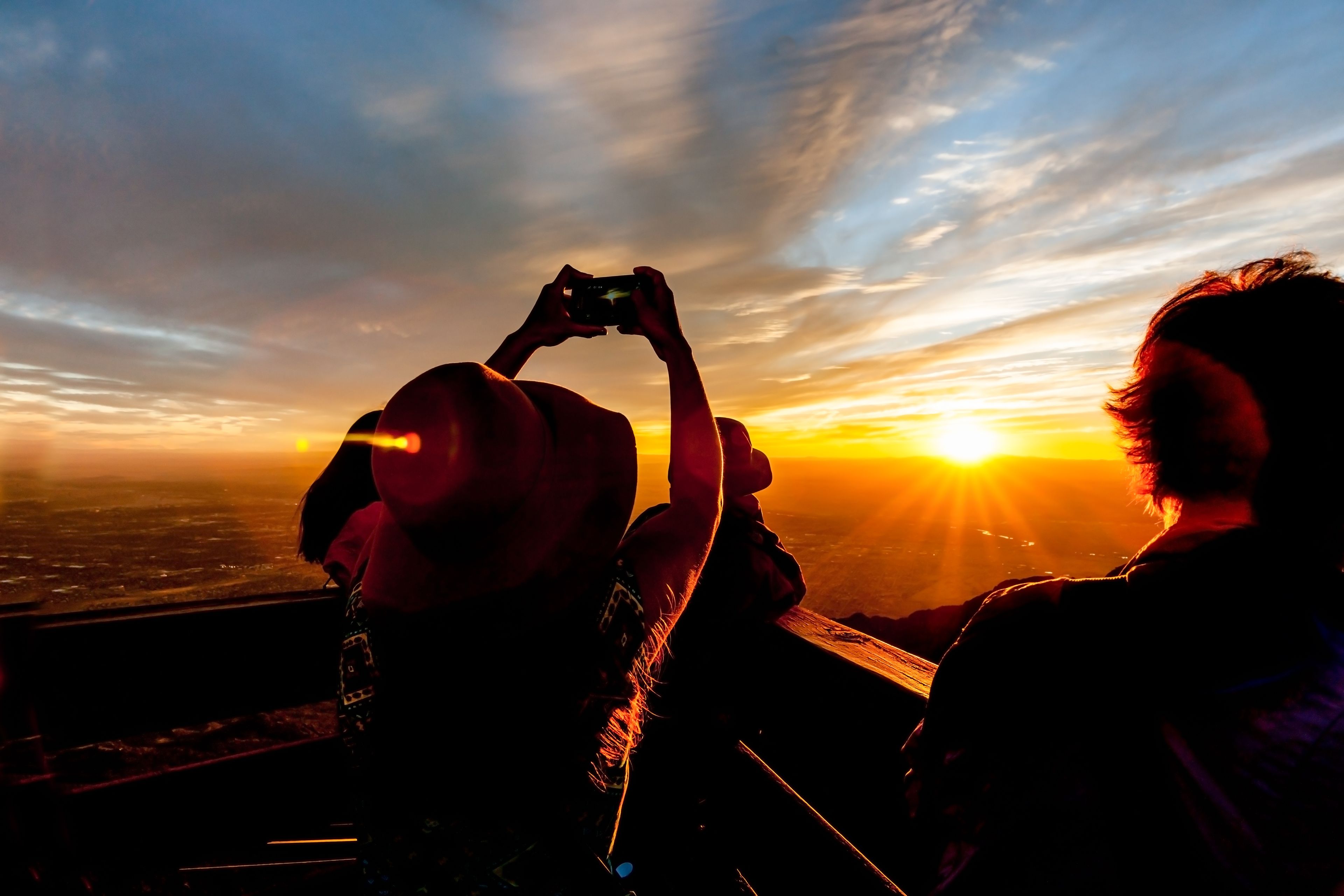 A person taking a photo of a sunset with the sun low on the horizon.