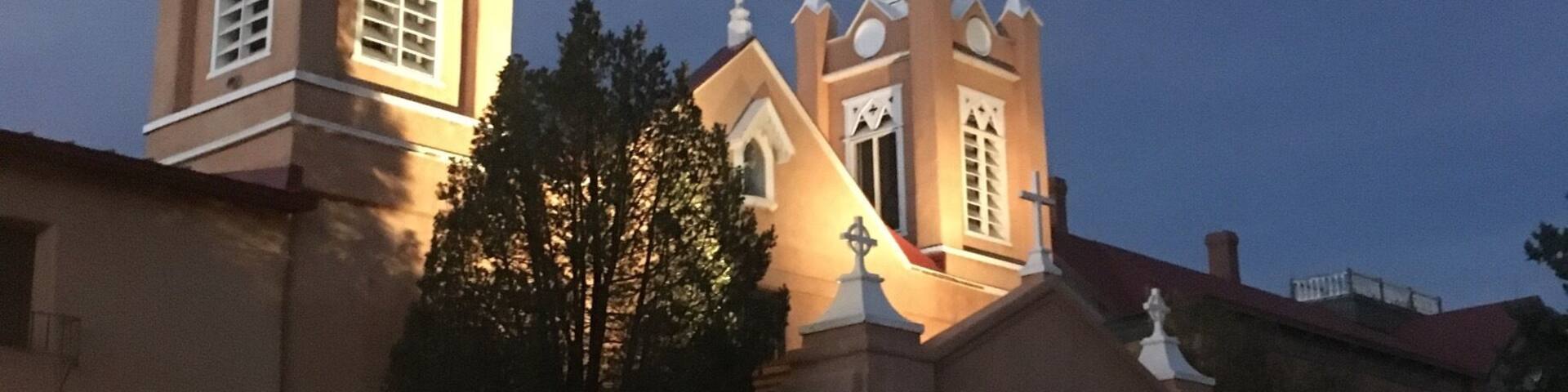 Une église dotée de deux tours et d’un dôme central, entourée d’arbres et de bâtiments.