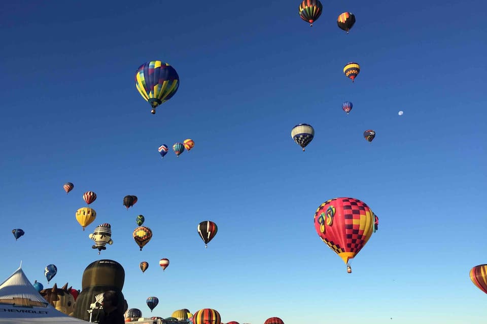 Un festival di mongolfiere con palloni aerostatici dai colori diversi in cielo.