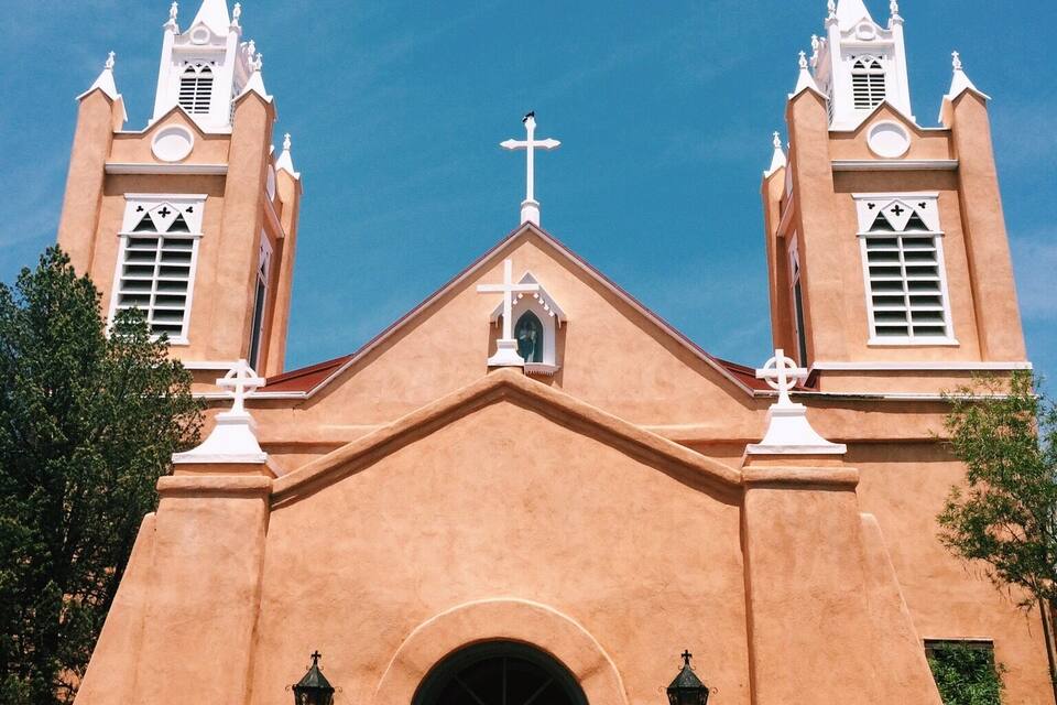 A church with two towers, a central entrance, and a cross on top.