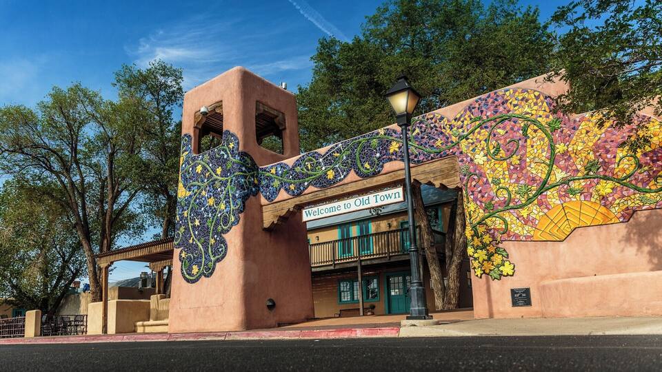 A building with a mosaic mural and a sign that reads "Welcome to Old Town."