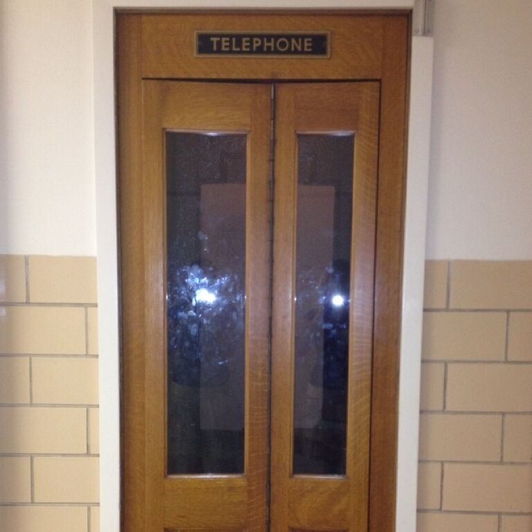 Old-school phone booth in Northrop Hall.  The phone has been removed, but a stool remains inside and the doors still open & shut to give one a quiet box in which he or she may find a modicum of momentary privacy.  